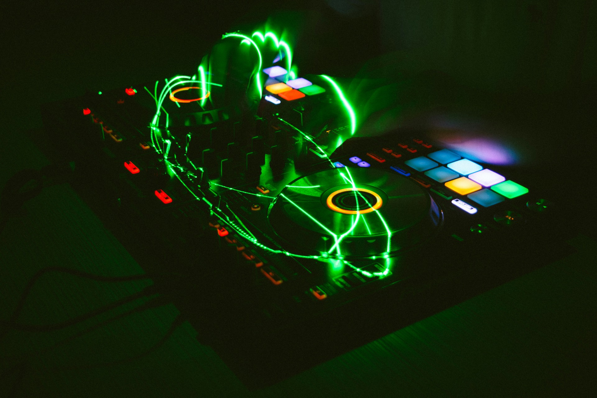 DJ-Controller mit gruenen Laserlinien im dunklen Raum
